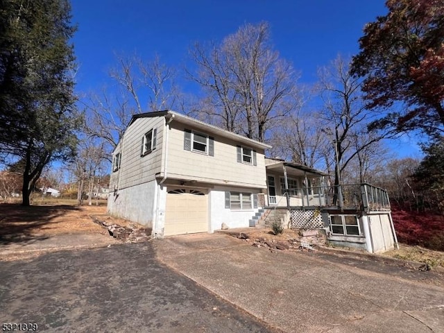 split level home with a porch, driveway, stairs, and a garage