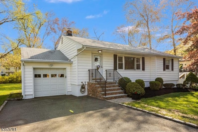 single story home with a front lawn, a garage, a chimney, driveway, and roof with shingles
