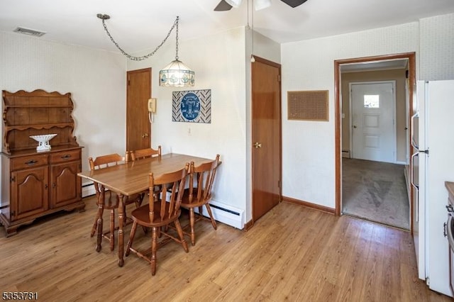 dining area featuring visible vents, wallpapered walls, baseboard heating, light wood-type flooring, and a ceiling fan