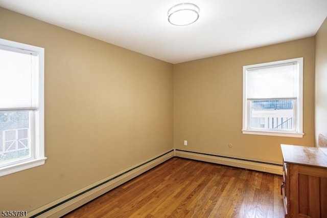 empty room featuring wood finished floors and a baseboard heating unit