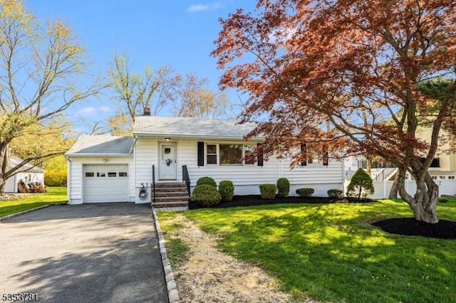 single story home with a front yard, a chimney, a garage, and aphalt driveway