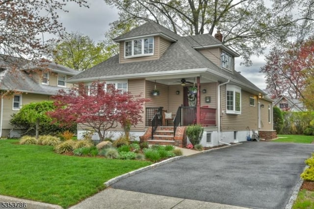 view of front of property featuring a porch, roof with shingles, ceiling fan, and a front yard