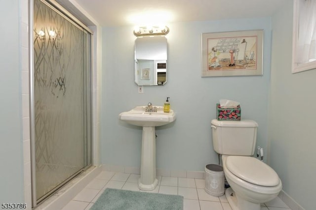 bathroom with baseboards, tile patterned flooring, a shower stall, and toilet