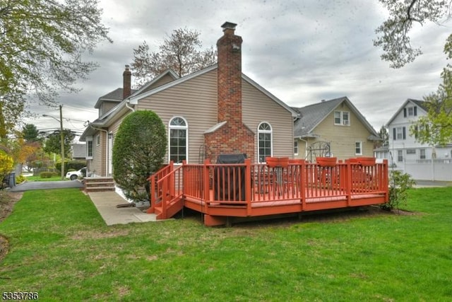 back of property featuring a yard, a deck, and a chimney