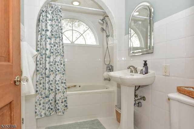 full bathroom with toilet, tiled shower / bath, and tile walls