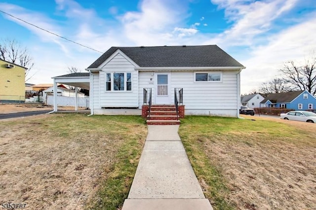 bungalow-style house featuring fence, a carport, and a front lawn