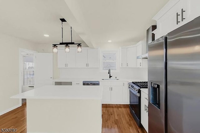 kitchen featuring a sink, stainless steel refrigerator with ice dispenser, a kitchen island, gas stove, and wood finished floors