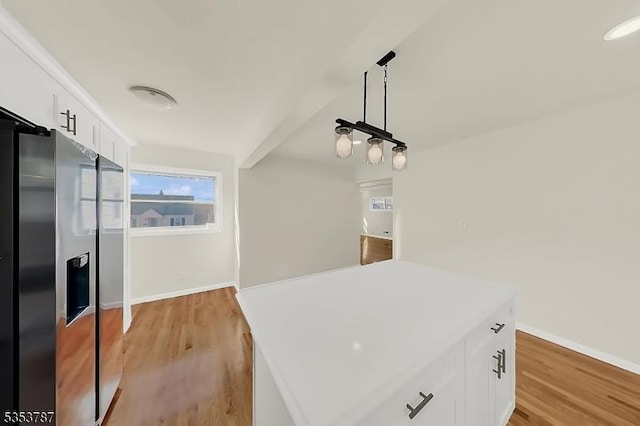 kitchen with light wood finished floors, stainless steel refrigerator with ice dispenser, white cabinetry, and baseboards