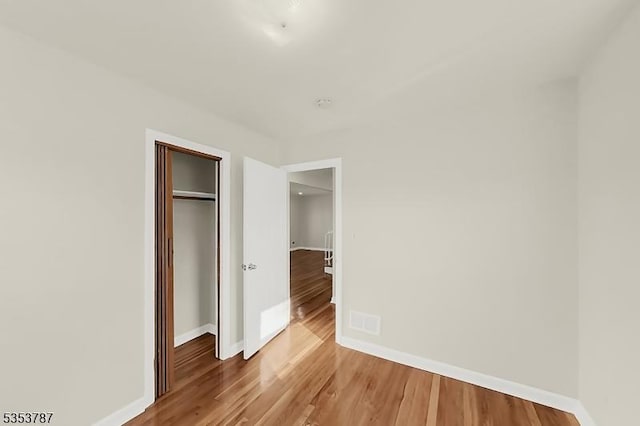 unfurnished bedroom with wood finished floors, a closet, and baseboards