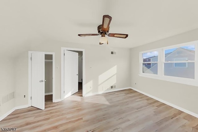 unfurnished bedroom featuring light wood finished floors, visible vents, a spacious closet, and baseboards