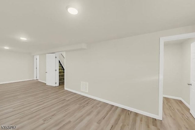 finished basement with light wood finished floors, recessed lighting, stairway, and baseboards