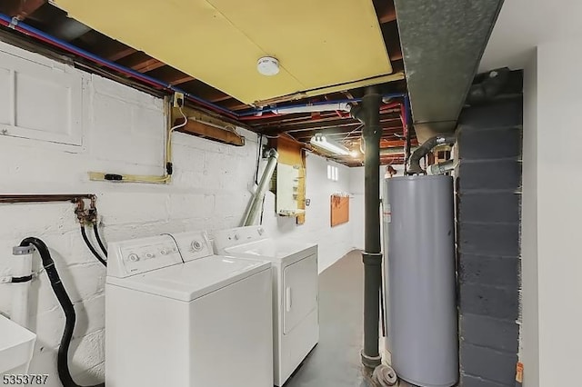 clothes washing area featuring water heater, separate washer and dryer, and laundry area
