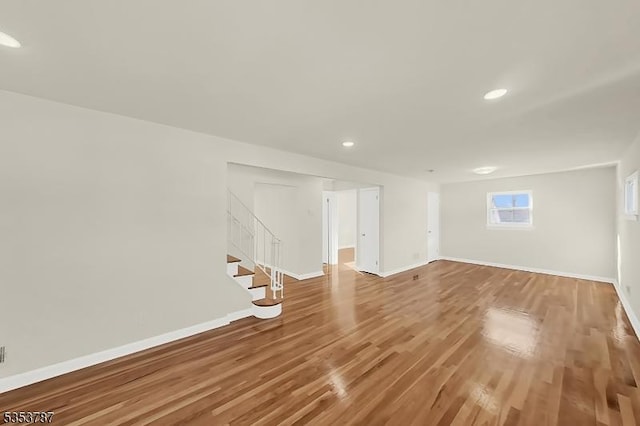 basement featuring wood finished floors, baseboards, recessed lighting, and stairs