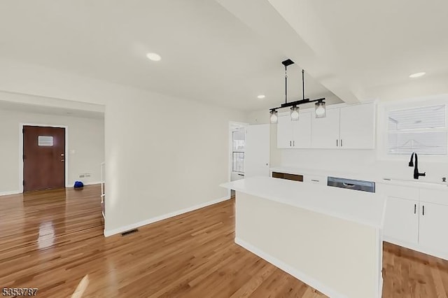 kitchen featuring a sink, baseboards, white cabinetry, and light countertops
