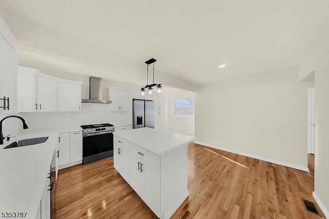 kitchen featuring a sink, stainless steel appliances, light wood-style floors, a center island, and wall chimney exhaust hood