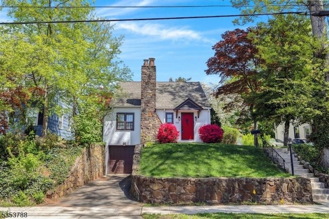 view of front of house with stairs, an attached garage, stucco siding, a chimney, and driveway