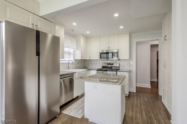 kitchen featuring a sink, backsplash, stainless steel appliances, and white cabinetry