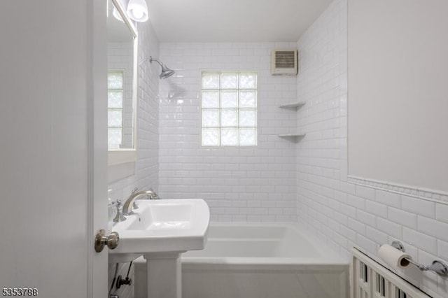 full bath featuring tile walls, visible vents, and bathtub / shower combination
