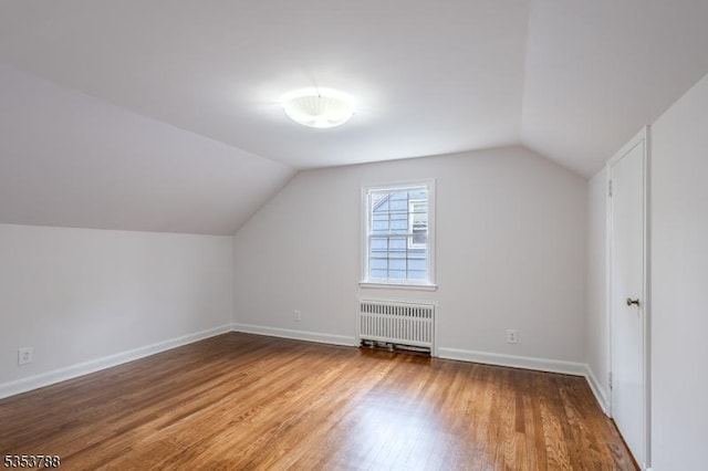 bonus room with baseboards, lofted ceiling, wood finished floors, and radiator