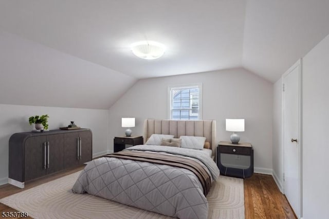 bedroom featuring baseboards, wood finished floors, and lofted ceiling