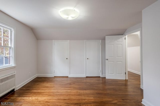 unfurnished bedroom featuring baseboards, lofted ceiling, wood finished floors, and radiator