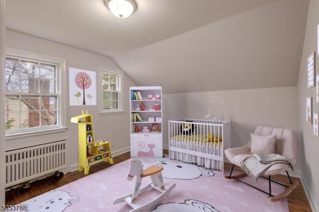bedroom with radiator, baseboards, wood finished floors, and lofted ceiling
