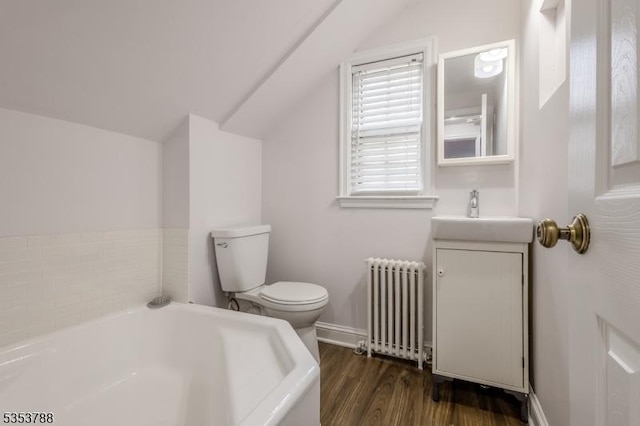bathroom with a garden tub, wood finished floors, vanity, toilet, and radiator