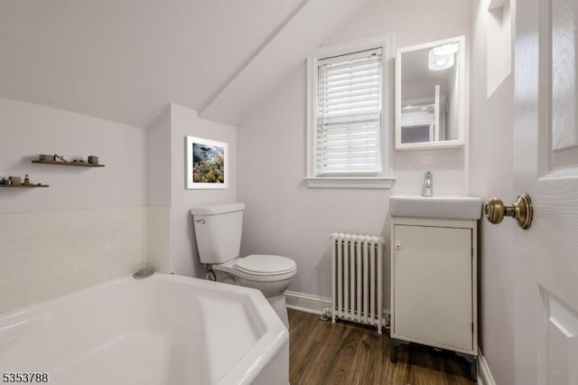 bathroom featuring a garden tub, radiator, lofted ceiling, wood finished floors, and toilet