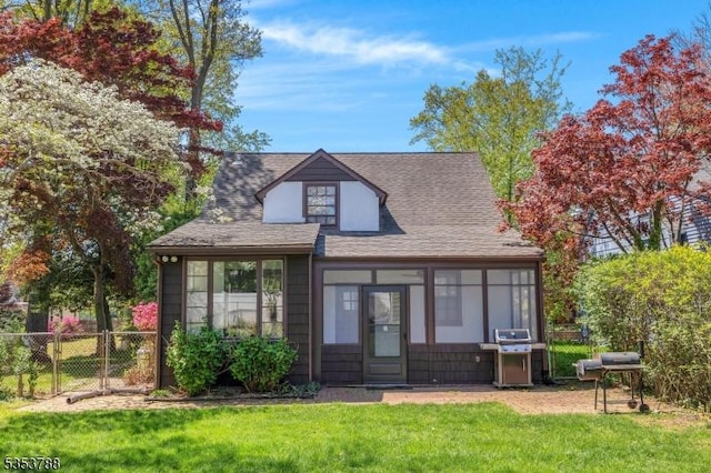 view of front of home with fence, roof with shingles, and a front lawn