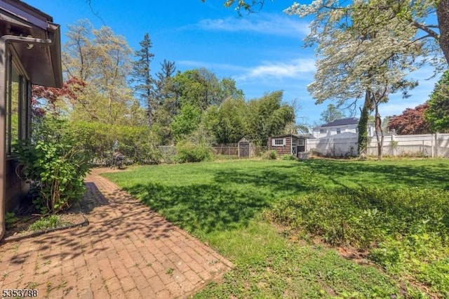 view of yard featuring an outdoor structure, a storage shed, a fenced backyard, and a patio area