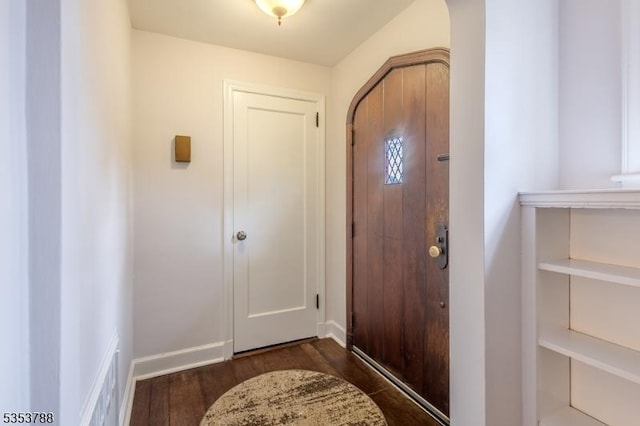 foyer featuring arched walkways, baseboards, dark wood finished floors, and visible vents