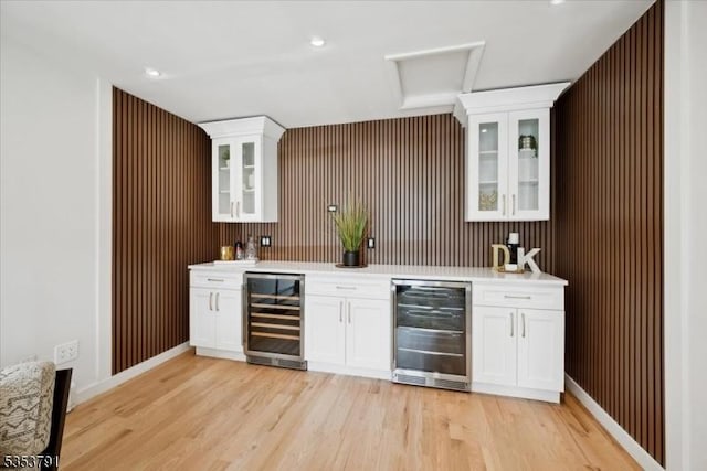 bar with beverage cooler, light wood-type flooring, and indoor wet bar