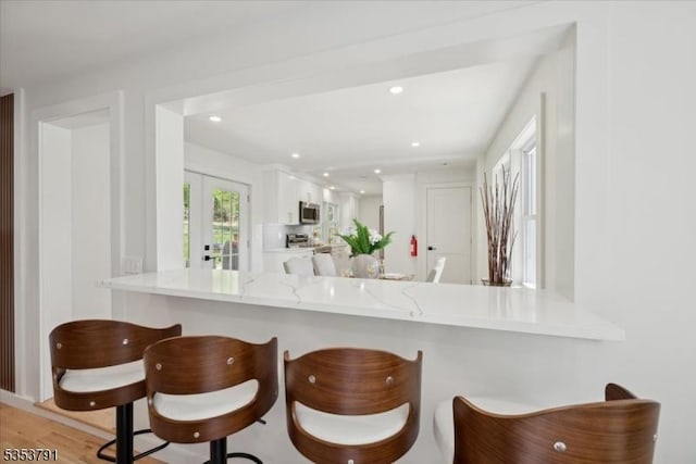kitchen with a kitchen breakfast bar, stainless steel appliances, a peninsula, and white cabinetry