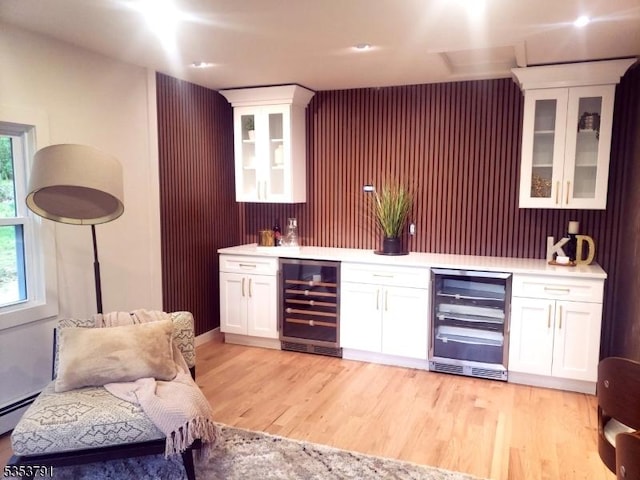 bar featuring bar, light wood-style flooring, beverage cooler, and a wealth of natural light
