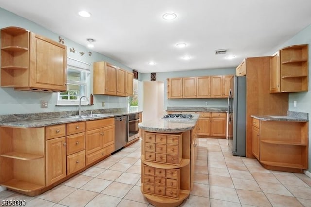 kitchen with open shelves, a sink, appliances with stainless steel finishes, light stone countertops, and a center island