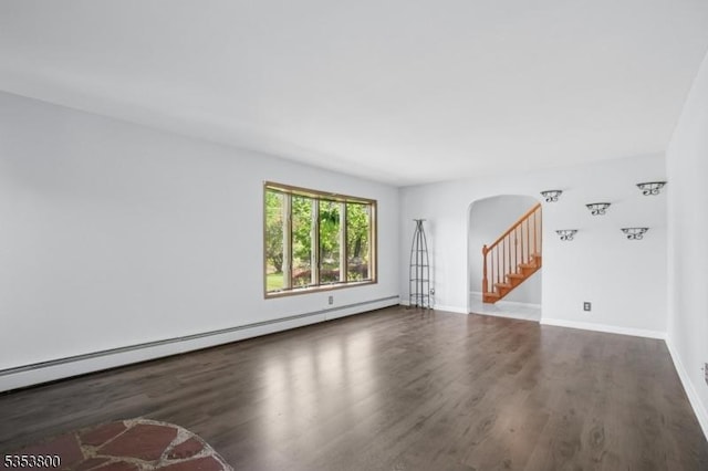 unfurnished living room with arched walkways, wood finished floors, a baseboard radiator, and baseboards