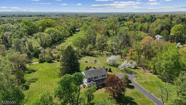 aerial view of property and surrounding area featuring a heavily wooded area