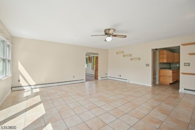 spare room featuring a baseboard heating unit, a ceiling fan, and plenty of natural light