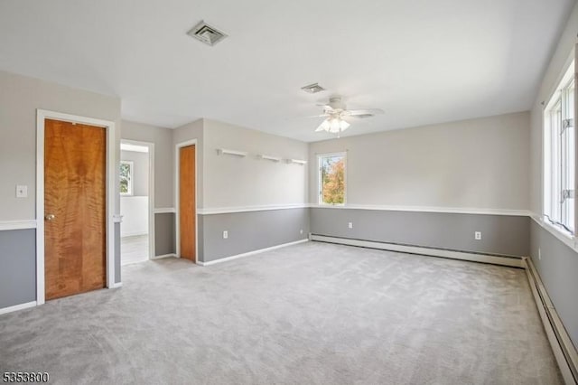 carpeted spare room with healthy amount of natural light, ceiling fan, and baseboard heating