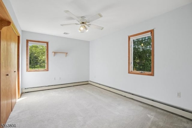 carpeted empty room with ceiling fan and a baseboard heating unit