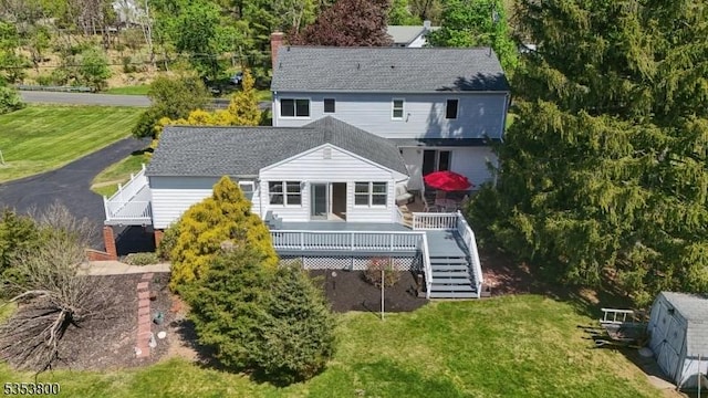 back of house featuring stairway, a wooden deck, a lawn, and roof with shingles