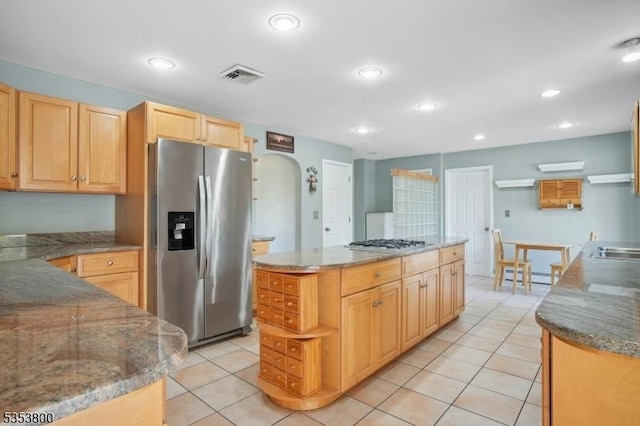 kitchen featuring appliances with stainless steel finishes, light tile patterned flooring, light brown cabinets, recessed lighting, and arched walkways