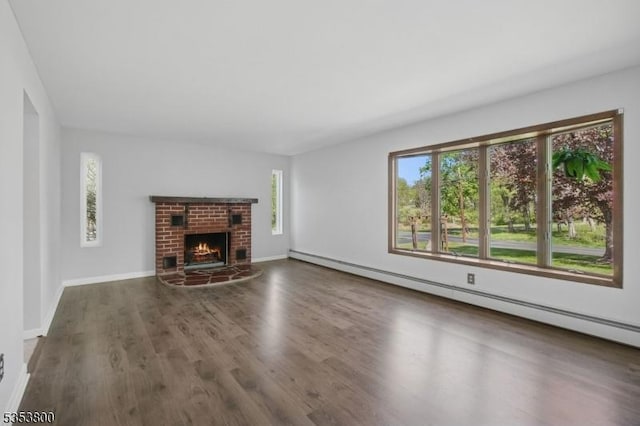 unfurnished living room featuring wood finished floors, a baseboard heating unit, baseboards, and a brick fireplace