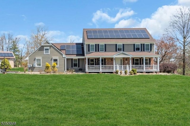 back of house with a porch, a shingled roof, a yard, and solar panels