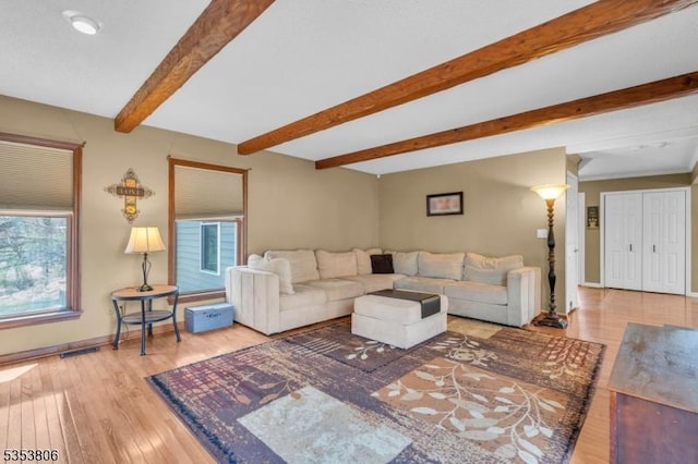 living area featuring wood finished floors, baseboards, beam ceiling, and visible vents