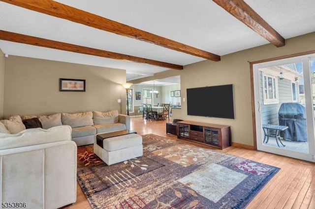 living room featuring baseboards, beam ceiling, and wood finished floors