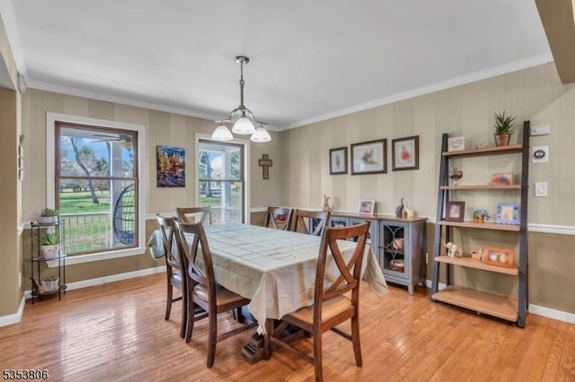 dining room featuring crown molding, light wood-style flooring, and baseboards