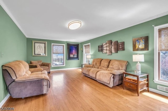 living area with baseboards, visible vents, ornamental molding, and wood finished floors