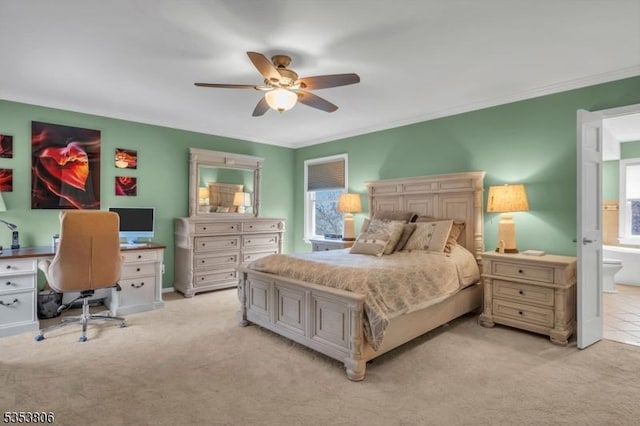 bedroom featuring ensuite bathroom, light carpet, ornamental molding, and ceiling fan