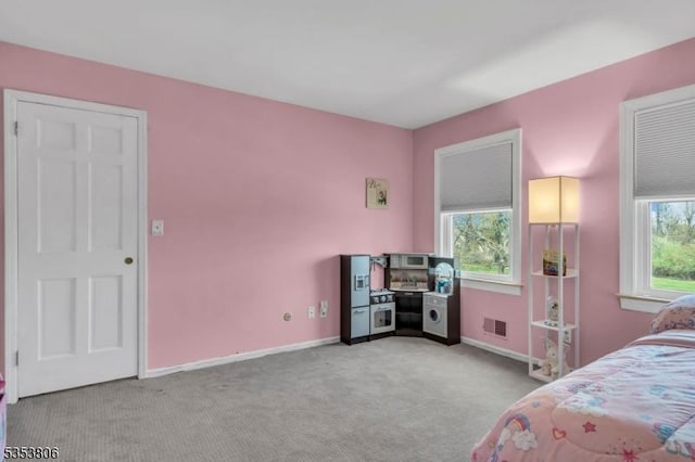 bedroom with baseboards, visible vents, and light colored carpet